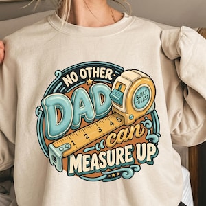 May include: A beige crewneck sweatshirt featuring a graphic design with a yellow tape measure and the text NO OTHER DAD can MEASURE UP and BUILT TO LAST. The illustration uses blue, orange, and cream colours in a circular, stylized layout.