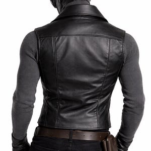 May include: Black leather vest with a notched collar, worn over a gray long-sleeve shirt. The person is wearing a black leather cap with goggles, black gloves, and black jeans. A brown leather belt and a brown leather pouch complete the look.