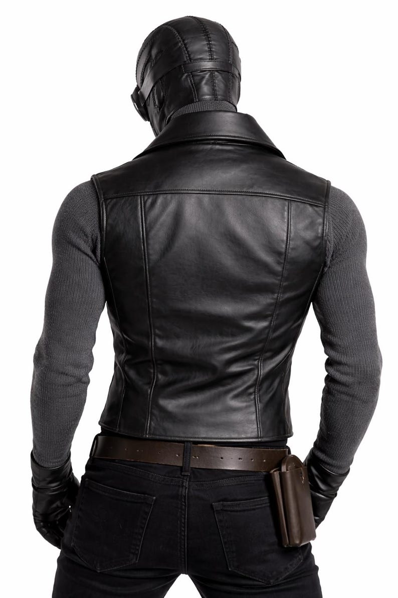 May include: Black leather vest with a notched collar, worn over a gray long-sleeve shirt. The person is wearing a black leather cap with goggles, black gloves, and black jeans. A brown leather belt and a brown leather pouch complete the look.