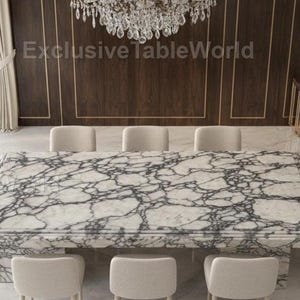 May include: A large rectangular marble dining table with a white and gray veined pattern, surrounded by eight beige upholstered chairs. A crystal chandelier hangs above the table. The room has a marble floor and dark wood paneling.