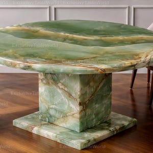 May include: A round, green onyx table with a square base and pedestal. The table has a polished surface with natural veining. The table is surrounded by four chairs with light-colored upholstery and wooden legs. The table measures approximately 122 cm in diameter.