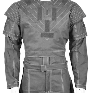 May include: A gray uniform with white stitching, featuring a long-sleeved top with shoulder pads and a matching pair of pants. The top has a chevron design and several rectangular patches. The pants have a belt and pockets.