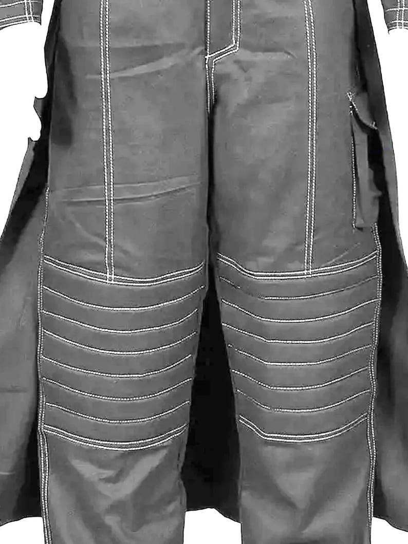 May include: Close-up of dark gray pants with white stitching. The pants have a quilted design on the knees and a pocket on the right leg. The pants are part of a larger outfit, with a coat visible on the sides.