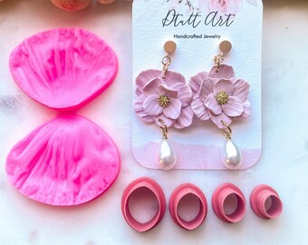 May include: Pink polymer clay flower earrings with pearl accents. The earrings are handmade and come with silicone moulds for making your own flower earrings. The card reads "Stutt Art Handcrafted Jewellery".