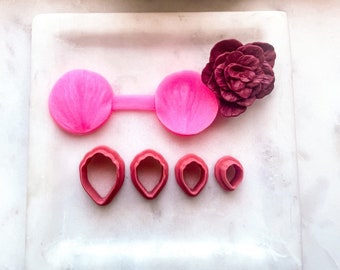 May include: A set of pink and red polymer clay tools for making flower petals. The set includes two large petal moulds, a rolling pin, and four smaller petal cutters.