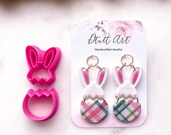 May include: A pair of handmade bunny and plaid egg earrings on a white card with the text "Dritt Art Handcrafted Jewelry".