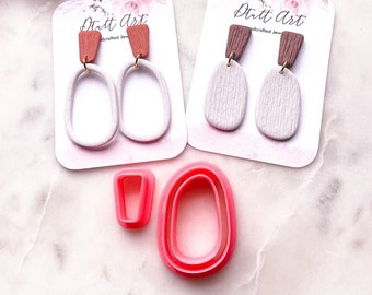 May include: Two pairs of handmade polymer clay earrings with a woodgrain texture. The earrings are white with brown and red clay accents. The earrings are displayed on white cards with the text "Dutt Art Handcrafted Jewelry".