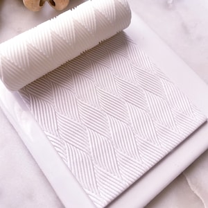 May include: White textured roller with a chevron pattern, rolling over a white textured surface with a chevron pattern.