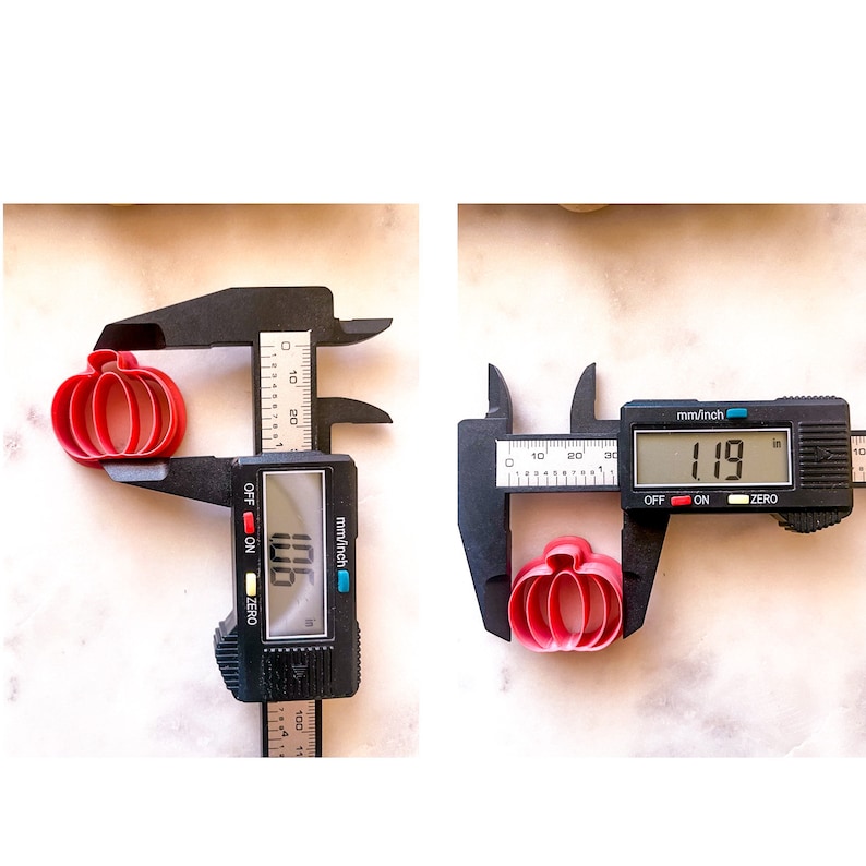 May include: Two red plastic pumpkin cookie cutters are measured with a digital caliper. The larger cutter measures 1.96 inches and the smaller cutter measures 1.19 inches.