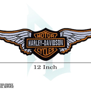 May include: A black, orange, and white Harley-Davidson Cycles patch, shaped like a shield with wings. The patch is 12 inches wide and features the brand's logo and text. The wings are white with orange trim.