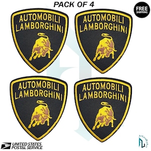 May include: Four black and gold embroidered Lamborghini patches. Each patch features the Lamborghini logo and text. The patches are shield-shaped with a gold border. The text "PACK OF 4" is at the top.