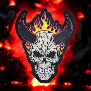 May include: Embroidered patch featuring a skull with horns and flames. The skull is off-white with black eyes and a wide grin. The horns are black with pink trim, and the flames are yellow and orange. The patch has a black border.