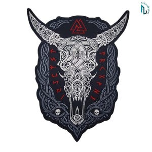 Op de afbeelding: Een zwarte geborduurde patch met een witte stierenschedel en ingewikkelde Keltische knooppatronen. Het ontwerp bevat een rood Valknut-symbool bovenaan, rode runentekst aan beide zijden en twee kleine witte schedels onderaan het kader.