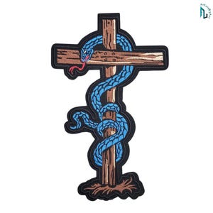 Puede incluir: Un parche bordado que muestra una cruz de madera marrón con una superficie texturizada. Una serpiente azul brillante con una lengua roja está enroscada alrededor de los travesaños verticales y horizontales. El diseño tiene un borde negro.