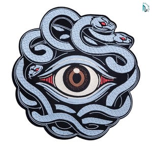 Könnte beinhalten: Ein kreisförmiger bestickter Aufnäher mit einem zentralen menschlichen Auge mit brauner Iris und weißer Sklera, umgeben von drei hellblauen Schlangen mit roten Augen. Das Design ist auf schwarzem Grund mit dickem schwarzem Rand.