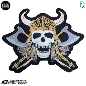 May include: Embroidered patch featuring a skull wearing a Viking helmet with crossed axes. The skull is white with a wide open mouth. The helmet is gold and the axes are gray. The patch is black with gold and tan accents. The words "FREE SHIPPING" are in a circle.