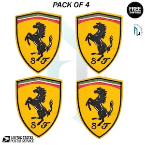 May include: Four yellow Ferrari shield patches with a black prancing horse logo. Each patch has a red, white, and green stripe at the top and the letters "SF" at the bottom. The text "PACK OF 4" is at the top.