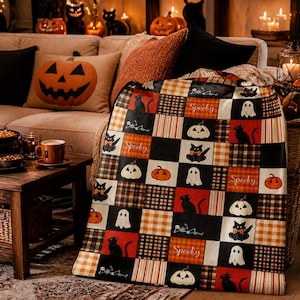 May include: A rectangular throw blanket featuring a patchwork design of Halloween-themed squares. The pattern includes black cats, white ghosts, orange pumpkins, skeletons, and plaid blocks in orange, black, and white. The word Spooky is printed.