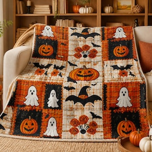 Könnte beinhalten: Eine rechteckige Wohndecke mit Patchwork-Design aus abwechselnden orangefarbenen und schwarzen Quadraten. Das Muster zeigt Illustrationen von weißen Geistern, orangefarbenen Kürbissen, schwarzen Fledermäusen und orangefarbenen Rosen auf kariertem Grund.