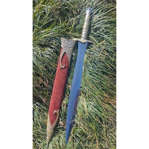 May include: A fantasy sword with a blue blade and ornate silver hilt rests beside its red sheath. The sheath has gold-colored decorative accents. The sword is lying on a bed of green grass.