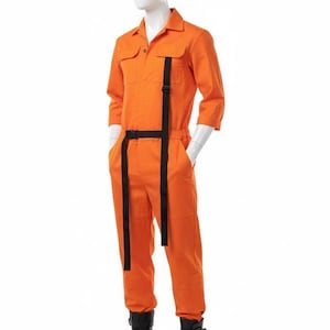 Może przedstawiać: Pomarańczowy kombinezon z czarnymi paskami i paskiem, prezentowany na manekinie. Kombinezon ma kołnierz, kieszenie i rękawy do trzech czwartych. Manekin ma na sobie czarne buty z klamrami.