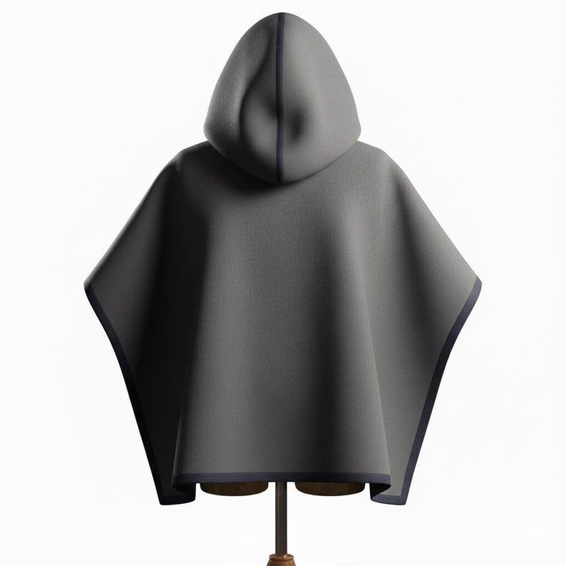 May include: A gray hooded cape with a dark blue trim. The cape is displayed on a wooden mannequin. The hood is a rounded shape and the cape has a simple, flowing design. The cape is made of a soft material.