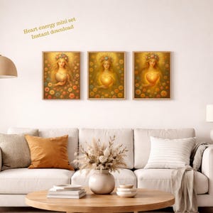Op de afbeelding: Drie ingelijste kunstprints met een vrouw die een gloeiend hart vasthoudt, omringd door bloemen. Het kunstwerk heeft een warm, gouden kleurenpalet. Tekst in de linkerbovenhoek luidt "Heart energy mini set Instant download."