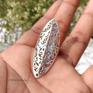 May include: A silver-colored ring with an elongated oval shape. The ring features an intricate openwork design with swirling patterns. The ring is held in a hand, and the text "925SilverRootJewelry" is visible at the bottom.