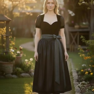 May include: A woman wearing a black dirndl dress with a sweetheart neckline, short sleeves, and a gray sash tied at the waist. The dress has a full skirt and is paired with black heels. The background is a garden with flowers and a stone path.
