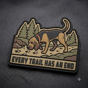 May include: A rectangular rubber patch featuring a tan and black hound dog tracking on a dirt path with pine trees in the background. The text "EVERY TRAIL HAS AN END" is printed in black capital letters along the bottom edge of the patch.