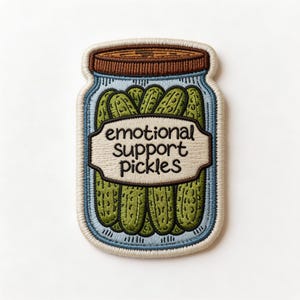 May include: Embroidered patch featuring a jar of pickles with the words "emotional support pickles" on a cream-colored label. The jar is blue with a brown lid, and the pickles are green. The patch has a light blue border.