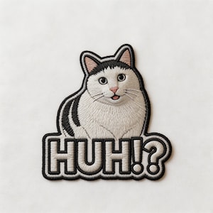 May include: Embroidered patch featuring a white cat with black markings, pink nose and ears, and a small pink tongue. The patch has the word "HUH!?" in a black outlined font.