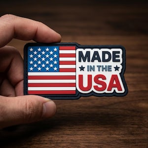 May include: A rectangular patch featuring the American flag design with red and white stripes and blue field with white stars. The text "MADE IN THE USA" is displayed in white and red.
