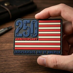May include: A rectangular patch featuring the American flag design with red and white stripes and a blue field with white stars. The number "250" in blue is at the top, with "ANNIVERSARY" below it. The text "INDEPENDENCE DAY OF AMERICA" is at the bottom.