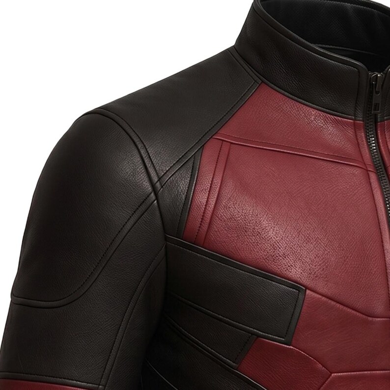 May include: A close-up of a red and black leather jacket. The jacket features a black collar, shoulders, and upper sleeves, with red panels on the chest and sides. The jacket has a zipper closure and detailed stitching.
