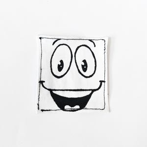 May include: A square white fabric patch featuring a black hand-drawn illustration of a cartoon face. The design includes two large oval eyes with pupils, arched eyebrows, and a wide, open-mouthed smile with a single tooth visible at the bottom.