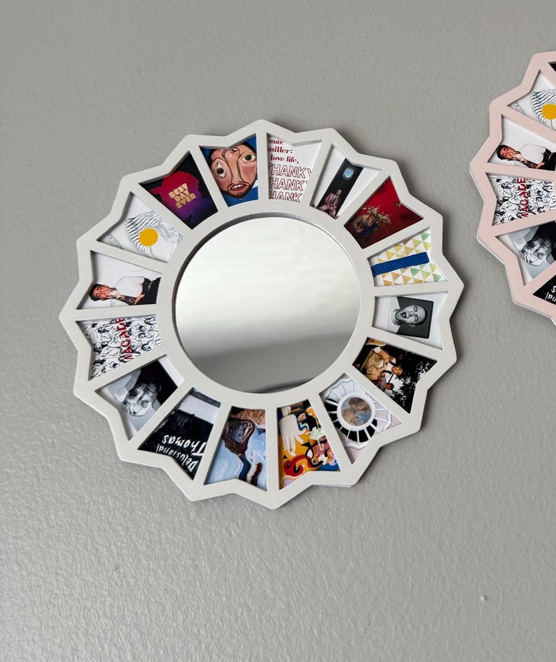 May include: A circular white frame with a starburst edge featuring a central round mirror surrounded by twelve trapezoidal photo slots. Each slot contains a different small image, including text that reads "BEST DAY EVER", "THANK YOU", and "Delusional Thomas".
