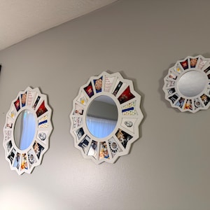 May include: Three white circular mirrors with scalloped edges, each featuring a decorative border composed of various small rectangular photo prints and colourful graphic images arranged in a radial pattern around the central glass surface.