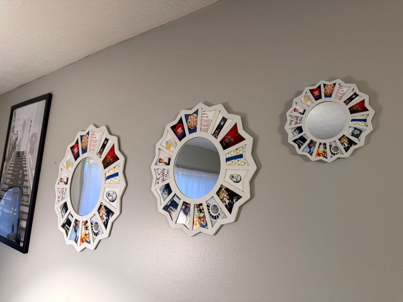 May include: Three white circular mirrors with scalloped edges, each featuring a decorative border composed of various small rectangular photo prints and colourful graphic images arranged in a radial pattern around the central glass surface.