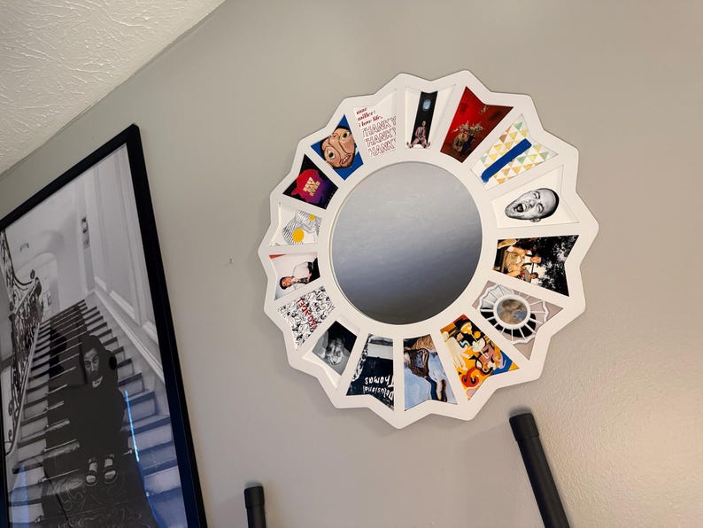 May include: A white, star-shaped wall mirror featuring a circular centre and twelve surrounding triangular compartments. Each compartment contains a distinct, colourful graphic illustration or photograph, creating a collage effect around the mirror.