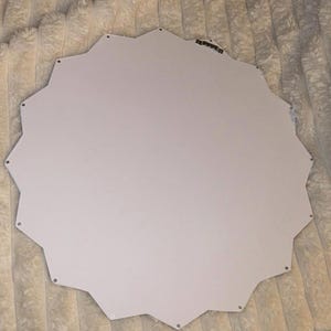 May include: A white, star-shaped wall mirror backing with a smooth, flat surface. The edges feature a jagged, multi-pointed silhouette. A small, metallic sawtooth hanger is attached to the upper portion of the back for mounting purposes.