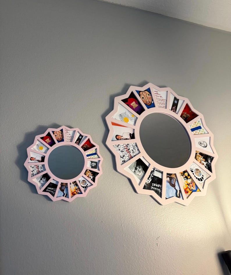 May include: Two circular mirrors with light pink frames, each featuring a sunburst-style border composed of multiple small, trapezoidal photo slots surrounding the central glass. The frames hold various colourful printed images in each slot.