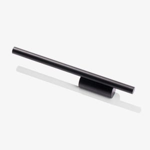 May include: A minimalist black metal desk clock with a cylindrical base and a horizontal bar. The clock has a simple, modern design, casting a shadow on a white surface. The overall aesthetic is sleek and contemporary.