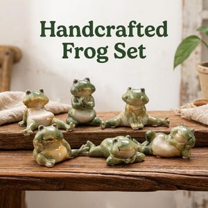 May include: A set of six ceramic frog figurines in various poses, featuring glossy green and cream glazes. The text Handcrafted Frog Set is displayed above the figures. The frogs are arranged in different positions, including sitting, reclining, and stretching on a wooden surface.