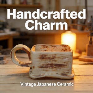 Op de afbeelding: Een handgemaakte, vierkante keramische mok met een handvat. De mok is gebroken wit met bruine accenten, en de tekst "Handcrafted Charm" staat bovenaan. De woorden "Vintage Japanese Ceramic" staan onderaan.