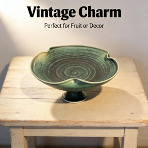 Könnte beinhalten: Eine türkisfarbene und schwarze Keramikschale mit Sockel. Die Schale hat einen wellenförmigen Rand und ein Spiralmuster in der Mitte. Der Text "Vintage Charm" und "Perfect for Fruit or Decor" steht oben.
