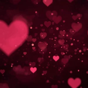 Op de afbeelding: Een donkerrode achtergrond met een bokeh-effect met talrijke roze harten van verschillende grootte. Sommige harten zijn scherp gefocust, terwijl andere wazig zijn, wat een romantische en dromerige sfeer creëert. Kleine, ronde, roze stippen zijn verspreid.