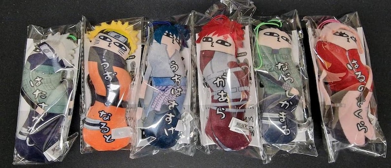 May include: Six plush character dolls in clear plastic packaging. Each doll features a different character with distinct hair and clothing colors. The dolls have Japanese text on them. The dolls are in a row on a black surface.
