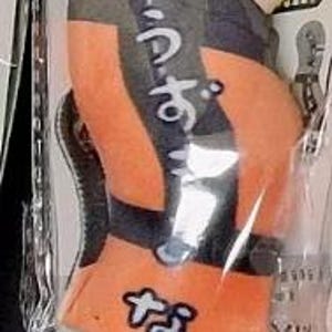 May include: Orange and black plush toy in a clear plastic package. The toy is shaped like a character with yellow hair, a headband, and Japanese text. The character is wearing an orange jumpsuit with black accents and a white and blue belt.