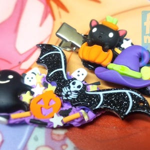 Può includere: Fermagli per capelli a tema Halloween con un pipistrello nero glitterato, un fantasma sorridente, un gatto nero in una zucca e un cappello da strega viola. Decorati con zucche e stelle arancioni.
